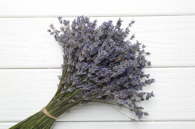 Beyaz ahşap masada lavanta çiçeği demeti, üst manzara.