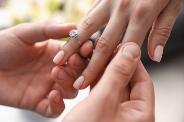 Evlenme teklif ediyorum. Adam içeride kız arkadaşının parmağına nişan yüzüğü takıyor.