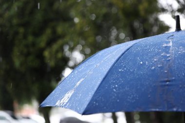 Dışarıda sağanak yağmur altında mavi şemsiye, yakın çekim. Metin için boşluk