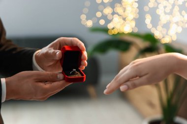 Nişan yüzüklü bir adam içeride kız arkadaşına evlenme teklif ediyor, yakın plan. Bokeh etkisi