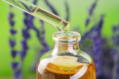 Lavanta yağı şişeye damlıyor. Arka plan bulanık, yakın plan.