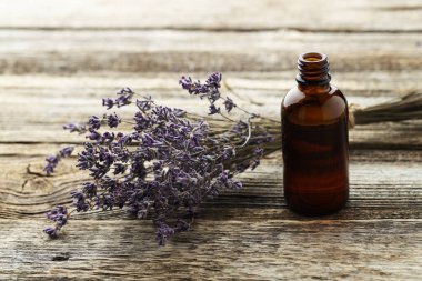 Lavanta yağı şişede ve çiçekler ahşap masada, yakın plan.