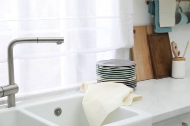 Mutfaktaki tezgahta temiz bulaşık takımı ve waffle havlusu var.