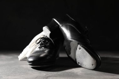 Step dansı için bir çift ayakkabı ve gri zeminde siyah arka planda beyaz eldivenler, yakın plan.