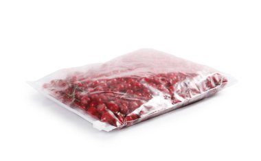Olgun donmuş kırmızı üzümler beyaz torbaya izole edilmiş plastik torbalarda.