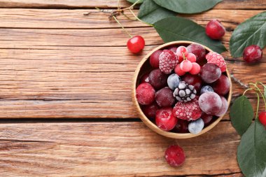 Olgun donmuş böğürtlen kasesi ve ahşap masada yeşil yaprakların karışımı. Metin için boşluk