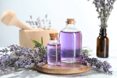 Beyaz mermer masa üzerinde lavanta çiçekleri ve şişelerde gerekli yağlar.