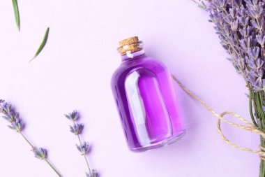 Aromatik yağ şişede ve lavanta çiçekleri menekşe arka planda, düz yatıyordu