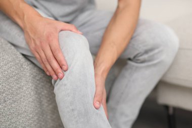 Kanepede diz ağrısı çeken bir adam, yakın plan.