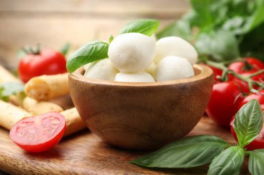 Lezzetli mozzarella peynir topları, domatesler, fesleğen ve Grissini masada, yakın plan.