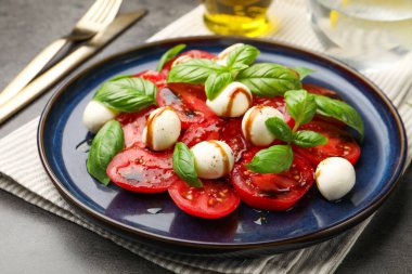 Caprese salatası. Gri masadaki balzamik sirkeyle servis ediliyor. Yakın plan.