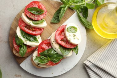 Mozarella peynirli, domatesli ve fesleğenli lezzetli sandviçler gri desenli masa, düz uzanış