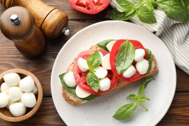 Peynirli, domatesli, ahşap masada fesleğenli lezzetli bir sandviç.