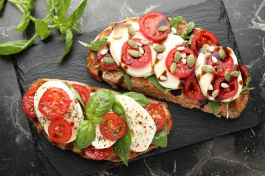 Mozarella peynirli lezzetli sandviçler ve siyah mermer masada domatesler.