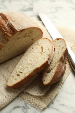 Beyaz mermer masada taze ekmek ve bıçak parçaları, yakın plan.