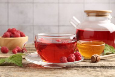 Lezzetli ahududu çayı, böğürtlen ve yapraklar ahşap masada, yakın plan.