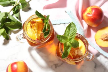 Buzlu şeftali çayını beyaz mermer masada naneli kavanozla tazeliyorum.