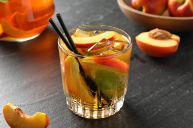 Bardakta buzlu şeftali çayı ve gri masada taze meyveler, yakın plan.