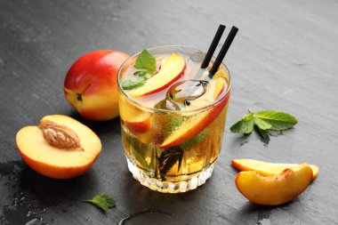 Bardakta buzlu şeftali çayı ve gri masada taze meyveler, yakın plan.