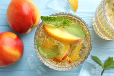 Şeftalili buzlu çay ve açık mavi ahşap masada nane.