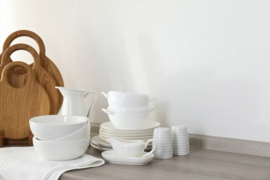 Mutfaktaki tezgahta farklı beyaz bulaşık takımları ve tahta kesme tahtaları var.