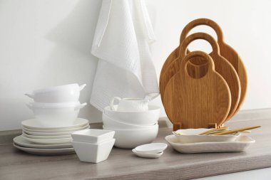 Mutfakta farklı beyaz bulaşık takımları ve tahta kesme tahtaları var.