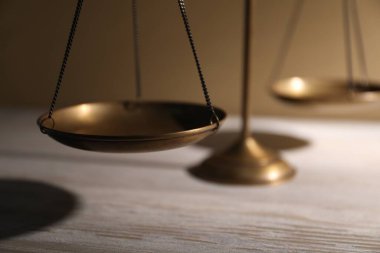 Tahta masanın üzerindeki adalet terazileri bej arka planda, yakın plan