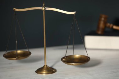 Adaletin terazisi, kitap ve hakimin tokmağı açık ahşap masa, gri arka plan, yakın çekim