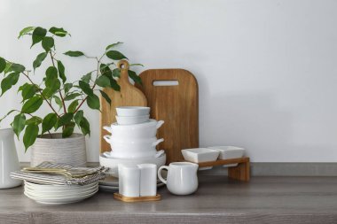 Farklı beyaz bulaşık takımları, ahşap kesim tahtaları, çatal bıçak takımı ve mutfak tezgahı.