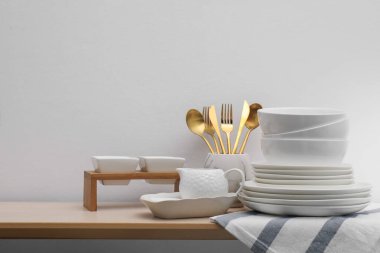 İçerideki ahşap masada farklı beyaz bulaşık takımları ve çatal bıçaklar.