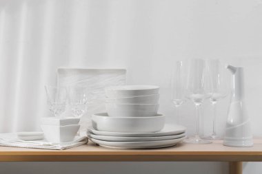 İçerideki ahşap masada farklı temiz beyaz bulaşık takımları ve bardaklar.