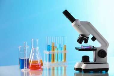 Işık masasının üzerinde farklı örnekler ve mikroskop bulunan laboratuvar camları.