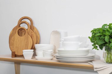 Temiz bulaşık takımları, tahta kesme tahtaları ve beyaz duvarın yanındaki tahta masada nane şekeri.