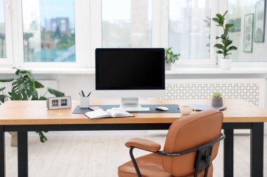 Modern bilgisayarı ve ahşap masa üzerindeki kırtasiyesi olan şık bir iş yeri.