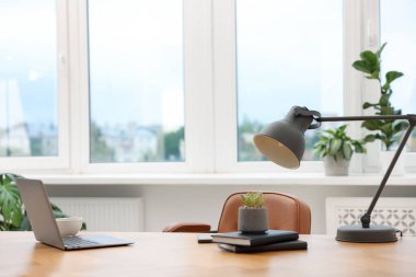 Modern dizüstü bilgisayarı ve ahşap masa üzerindeki kırtasiyesi olan şık bir iş yeri.