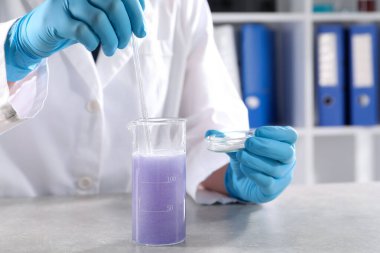 Laboratuvarda Gri Masa 'da numuneyle çalışan bir bilim adamı, yakın plan. Çözüm kimyası