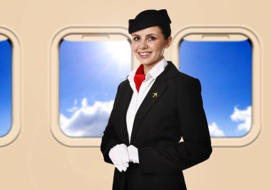 Hostes uçaktaki pencerelerin yanında gülümsüyor.