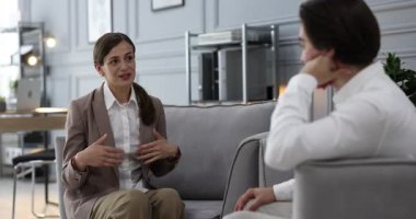 Ofisteki koltuklarda iş arkadaşıyla tartışan bir kadın.