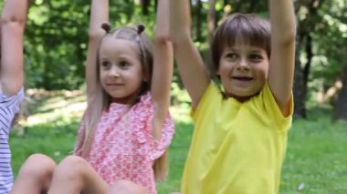 Parktaki yeşil çimlerde sevimli küçük çocuklar, sola hareket eden kamera.