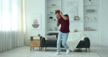 Evde müzik dinlerken zıplayan mutlu bir adam.