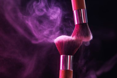 Siyah arka planda neon ışıklarıyla göz farı renginde makyaj fırçaları, yakın plan. Metin için boşluk