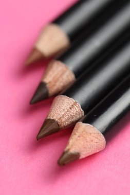 Pembe arka planda farklı kaş kalemleri, yakın plan.