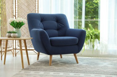 Pencerenin yanında, içinde perdeler olan şık bir mavi koltuk. İç tasarım