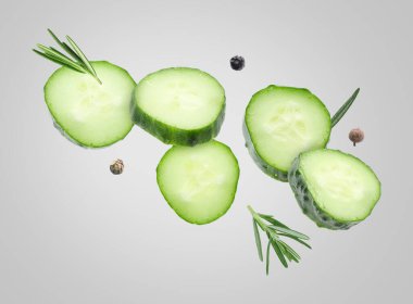 Salatalık dilimleri ve gri arka planda uçuşan biberiye