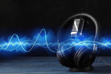 Kulaklıklar, mikrofon ve ses dalgaları siyah arkaplan karşısında