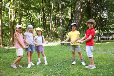 Parkta çekiştirmece oynayan sevimli küçük çocuklar.