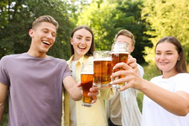 Bir grup mutlu arkadaş açık havada bira bardakları tokuşturuyor, seçici odaklanma.