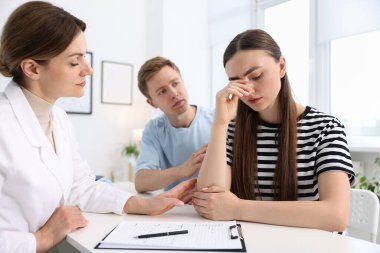 Tüp bebek (tüp bebek). Üreme kliniğinde doktorla randevusu olan üzgün çift.