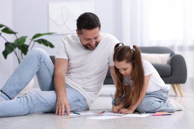 Baba ve kızı evdeki sıcak zeminde birlikte resim çiziyorlar. Isıtma sistemi