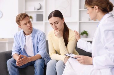 Tüp bebek (tüp bebek). Üreme kliniğine yaptığı ziyarette üzgün çifti destekleyen doktor